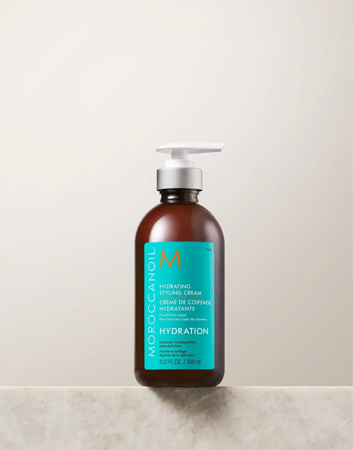 Moroccanoil Hydrating Styling Cream bottle with blue label on a simple beige background.