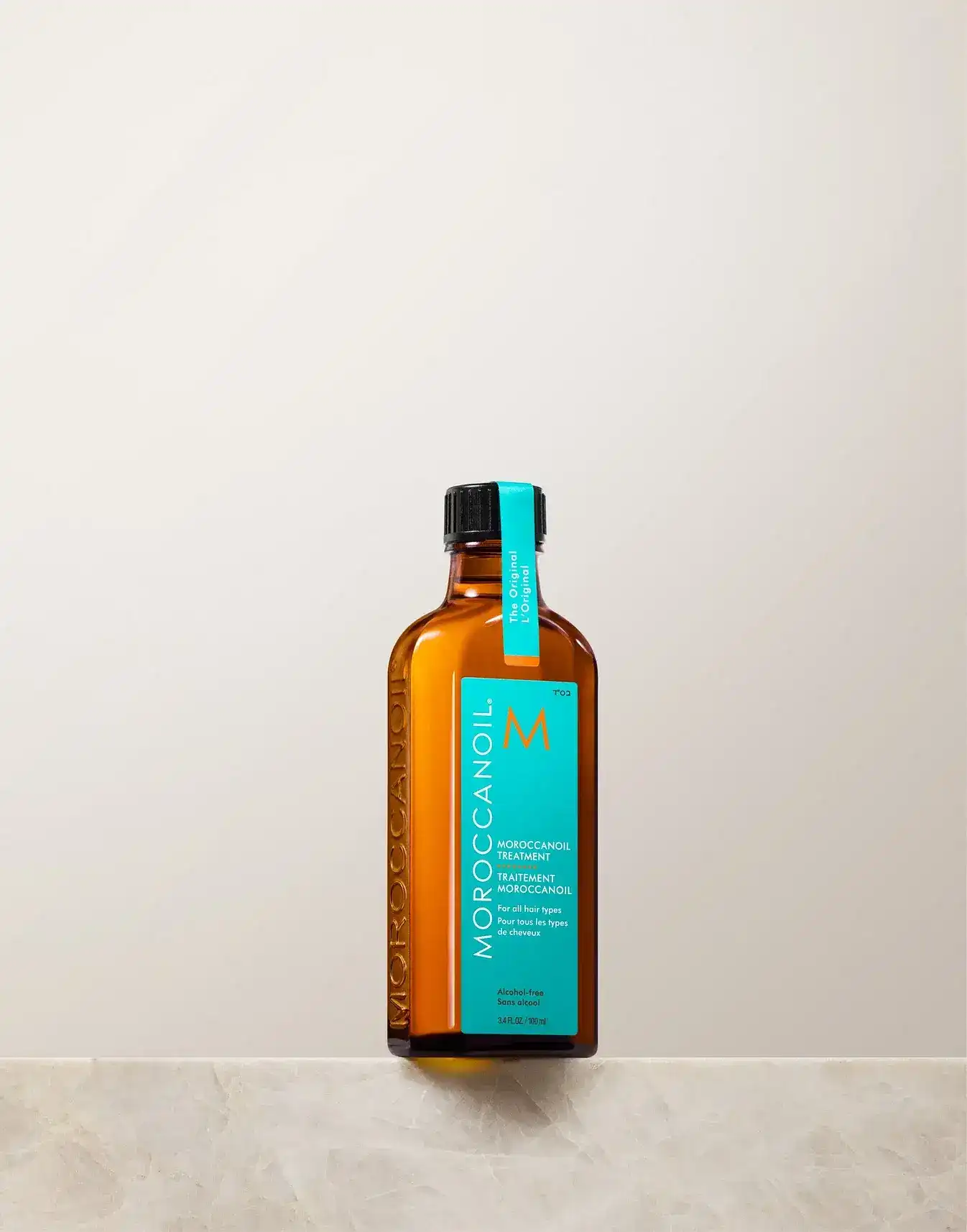 Moroccanoil Treatment bottle placed on a marble surface against a light background.